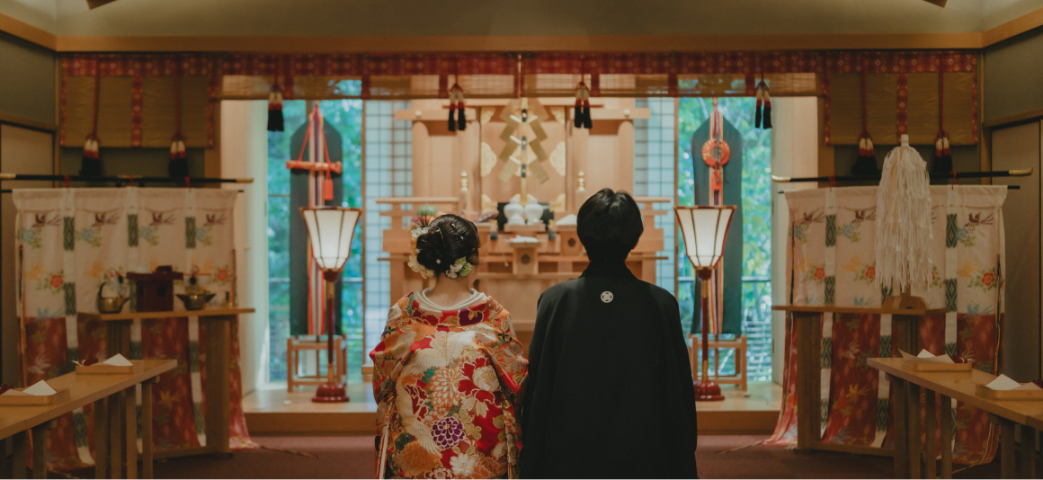 写真：神殿で神前式を行う、和装の婚礼衣装を着た新郎新婦